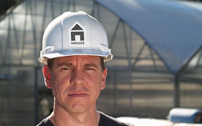 A male construction worker wearing a custom hard hat sticker on a white hard hat.