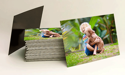 Stack of custom photo magnets. Magnet has a photo of a little blonde boy and his puppy playing outside.