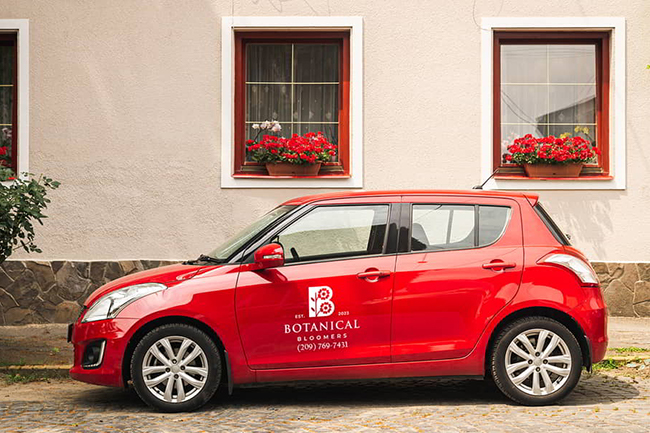 Red car in front of building with Botanical Bloomers Business Car decal