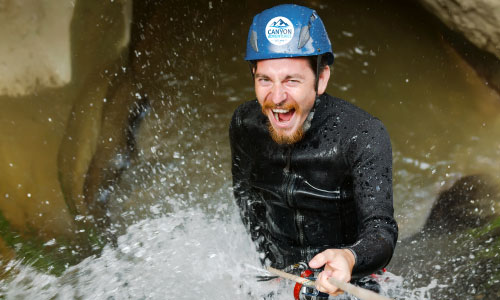 Man wearing a blue hard hat with a circle helmet label standing in rushing water