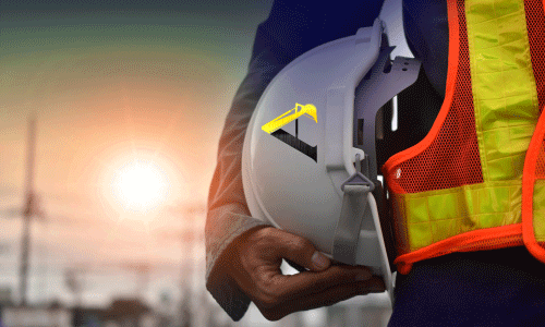 Reflective logo sticker on white hard hat being held at sunrise