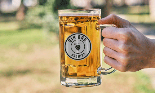 Man holding glass beer mug with black and white beer label