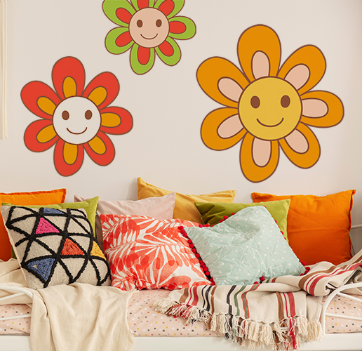Three flower wall stickers placed on a wall behind a cozy bed full of pillows