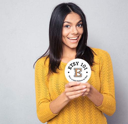smiling woman holding an Etsy sticker in her hands