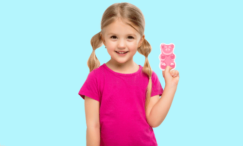 Blue background. Blonde little girl with pig-tails. She is wearing a bright pink shirt and holding a pink gummy-bear die-cut sticker.