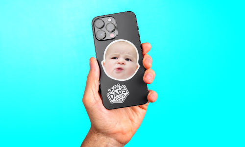 Hand holding phone with a baby face sticker on the back