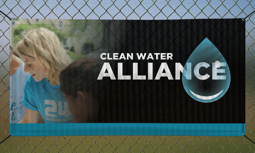 Mesh banner on a fence. There is a blonde woman on the banner and the text to the right says Clean Water Alliance. 